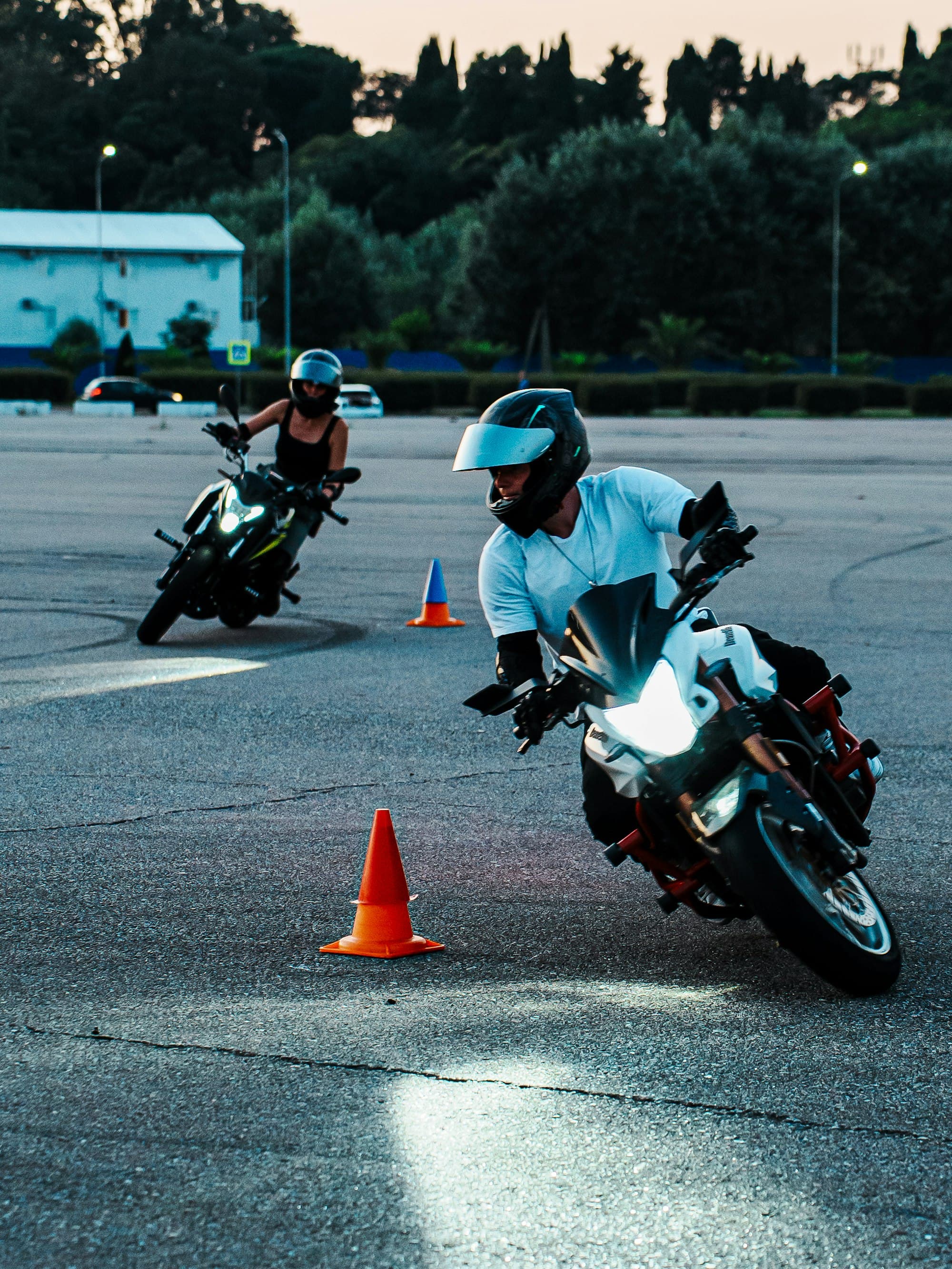 Kapalı alanda dubalar arasında motosiklet eğitimi yapan sürücüler